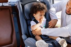 Little boy being secured by father in car seat