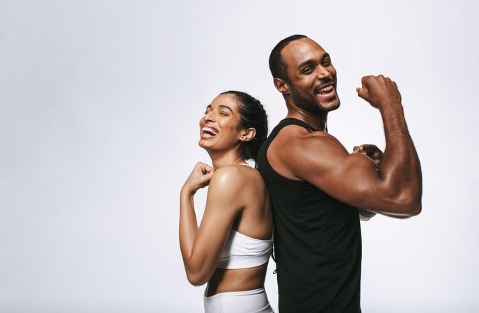 Athletic couple showing off arm muscles standing back to back