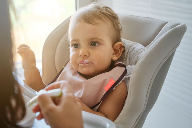 Crop woman feeding daughter with spoon