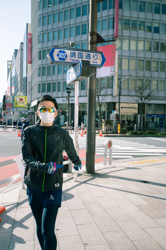 Man with facemask jogging on sidewalk in the city