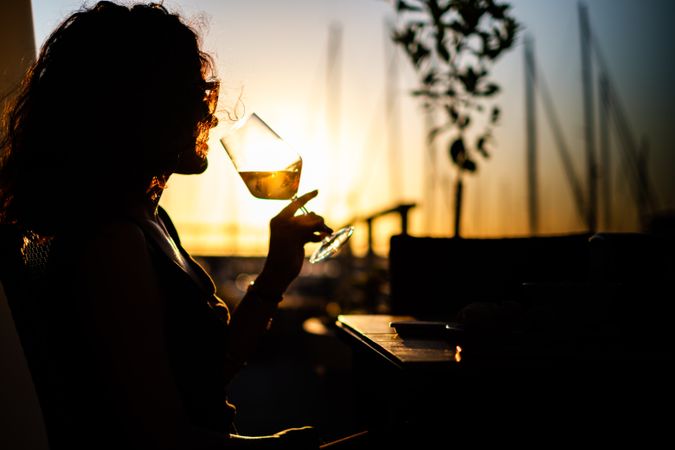 Silhouette of woman drinking wine during sunset