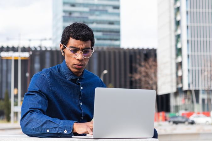 Serious male freelancer working on laptop in city
