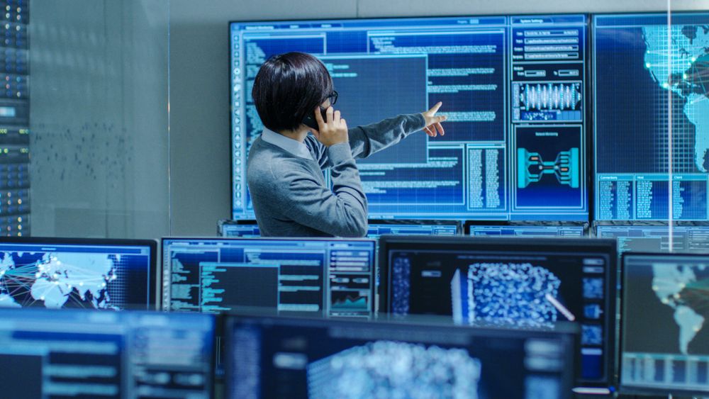In the System Control Room IT Administrator Talks on the Phone.