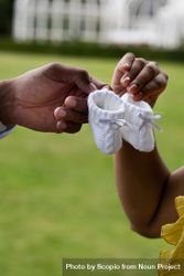 Cropped image of two hands holding baby shoes bEJR60