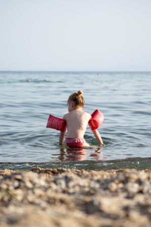 Girl wearing red floaties at the beach
