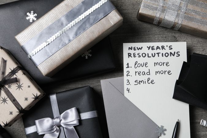 Paper with list and gift boxes on gray background, top view