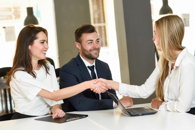 Two women shaking hands after meeting in bright office