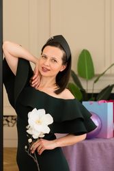 Woman posing with white flower, smiling at birthday party.
