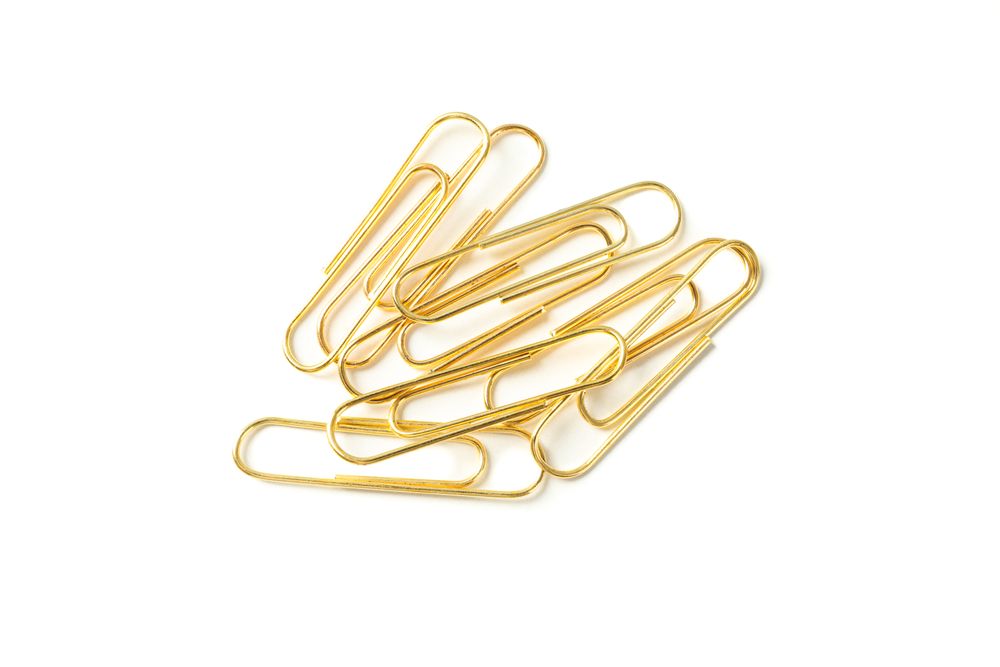 Gold paper clips isolated on studio background, closeup