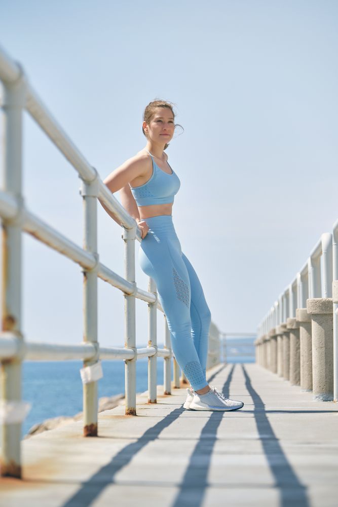 Fit sportswoman having break from workout on bridge over sea