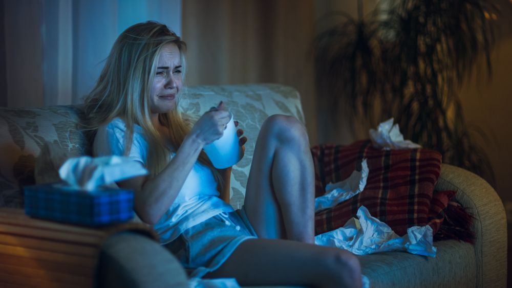 In the Evening Heartbroken Woman Sitting on a Sofa, Crying and Eating Ice Cream