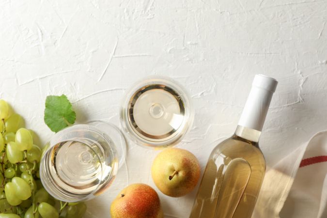 Pears, grape, bottle and glass with wine on plain background, top view