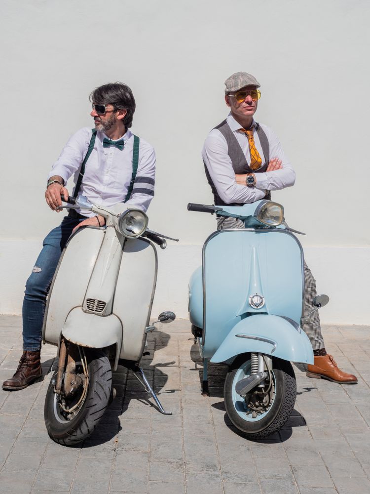 Trendy men sitting on vintage scooters