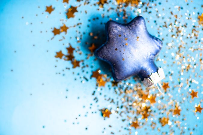 Festive xmas card concept of star glitter on star ornament on blue background