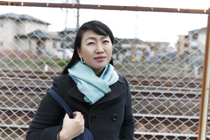 Portrait of woman in dark jacket standing beside fence outdoor