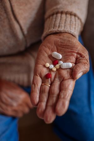 Detail of pills on the hand of an older man