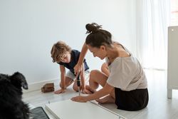 Focused mother and son assembling furniture together on floor