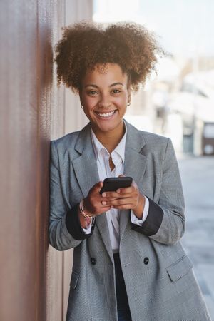 Content Black woman searching mobile phone against st