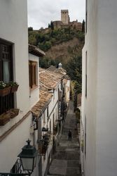 Joyful Asian resting female hiking on old rocked narrow street