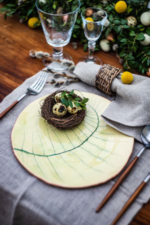 Festive table setting for Easter holiday dinner decorated with bird nest & eggs