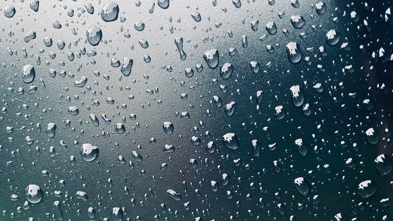 raindrops on a car windshield, blurring the view of the road ahead