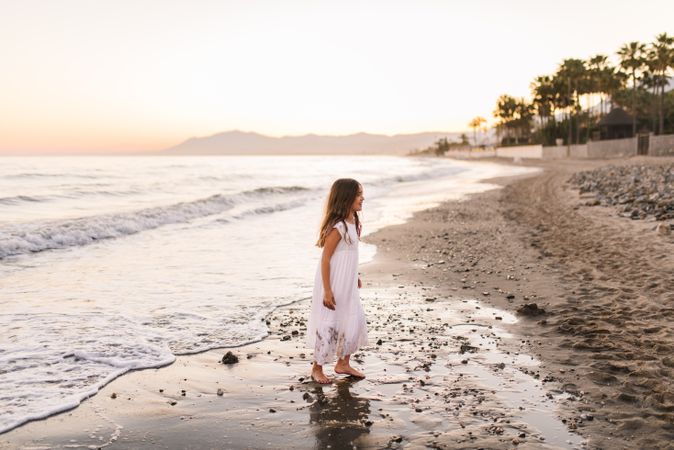 Excited girl running along beach in daylight