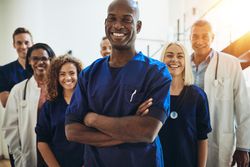 Smiling Black doctor with arms crossed pictured with medical team