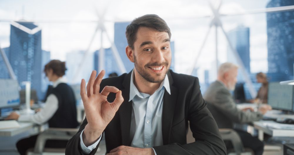 Point Of View From Camera With Handsome Entrepreneur Sitting Down On His Workplace In Diverse Skyscraper Office.
