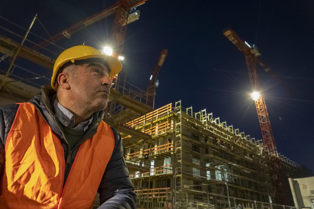 Construction worker beside a building under construction at night