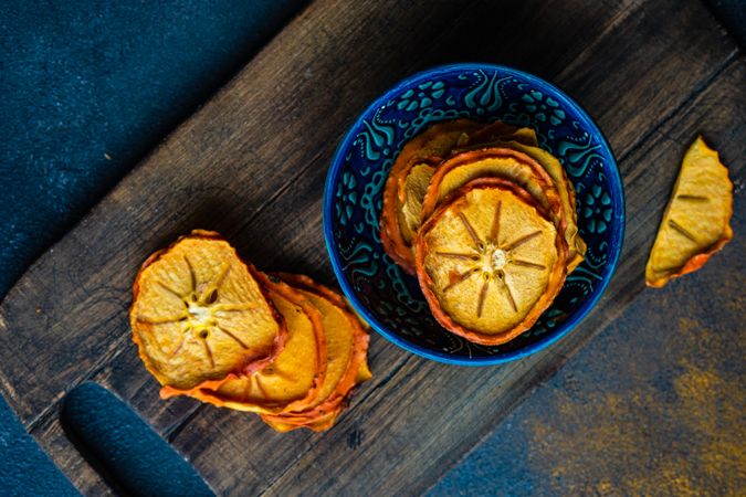 Dried persimmon fruits in bowl on board