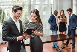 Two colleagues with clip board in busy office
