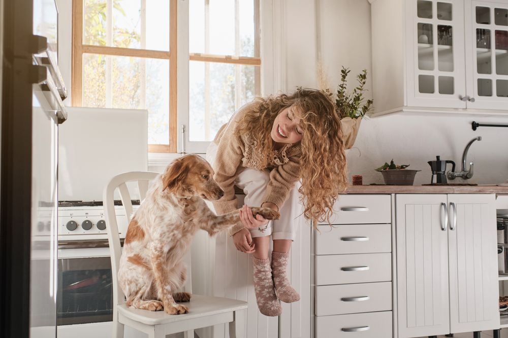 Happy woman with dog in kitchen