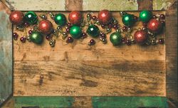 Tree ornaments on wooden board, large and small red, green and gold baubles, copy space