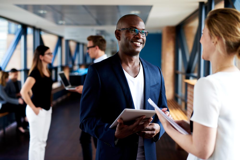 Businessman holding a tablet with female colleague in office hallway