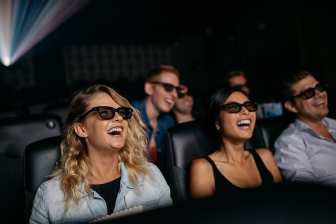 Group of friends watching 3d movie and laughing in cinema