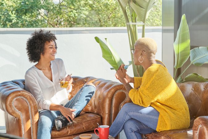 Cheerful multiracial women talking on couch