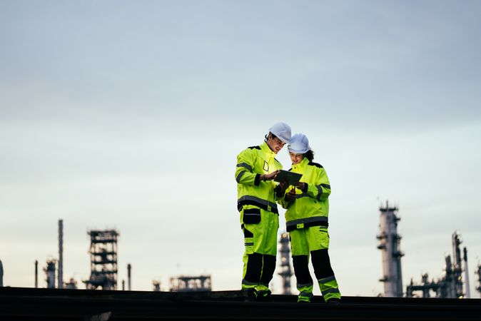 Engineer worker watching work monitor on digital tablet at refinery factory at night
