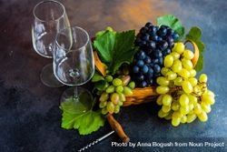 Box of fresh green & red grapes on grey kitchen counter with wine glasses bYqWAG