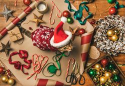 Festive scene of cat in a holiday sweater and Santa hat, with a wreath, candy canes