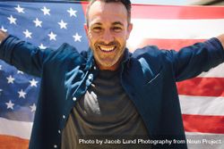 Close up of a smiling man holding American flag behind him 0vOjp5