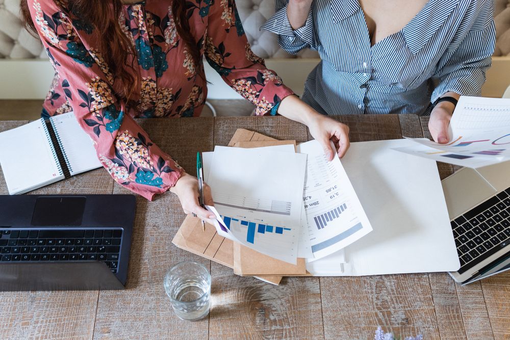 Crop focused female colleagues analyzing charts together in office