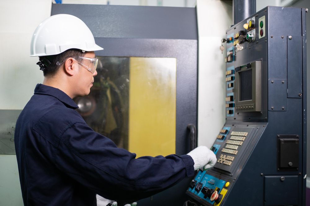 Man operating controls in construction site in safety helmet and coveralls