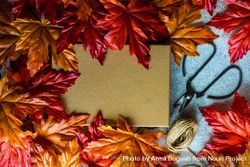 Giftbox with scissors and string surrounded with autumn leaves bYAzgb