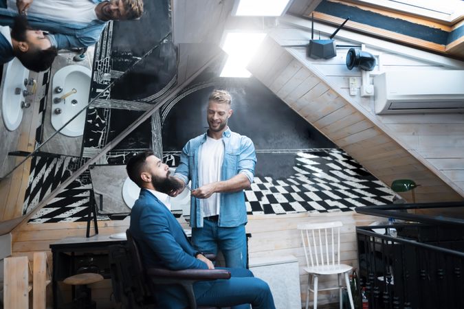 Man in blue suit having his beard trimmed in funky salon