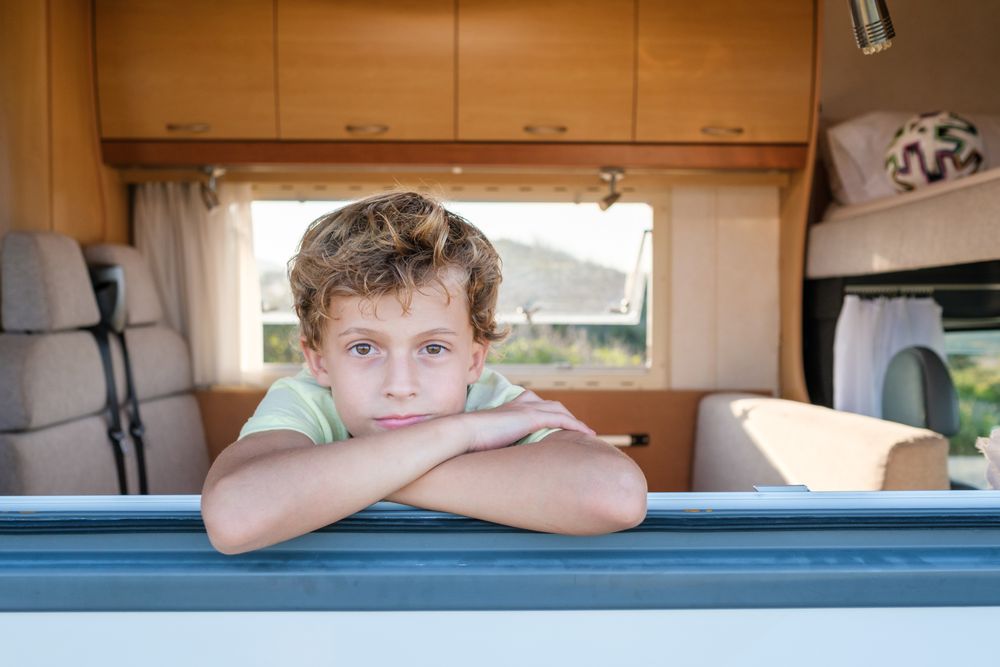 Calm boy looking at camera through camper window