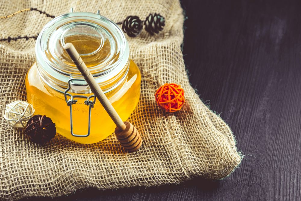 Small Jar of Honey and Dried Flower on Burlap