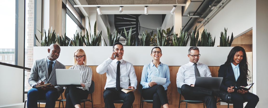 Group of people sitting in a row in a bright office