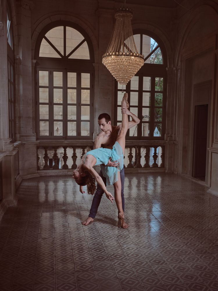 Ballerina doing standing split with help of partner in palace