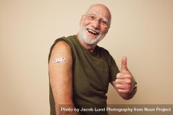 Portrait of a older male smiling and showing thumbs up after getting a vaccine 5qYV15