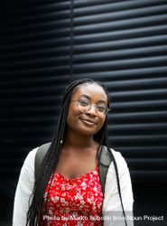 Smiling young Black woman in glasses against dark background 0Wmj64